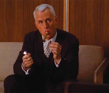 man wearing a suit and lighting a cigar