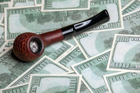 tobacco pipe laying on $100 bills