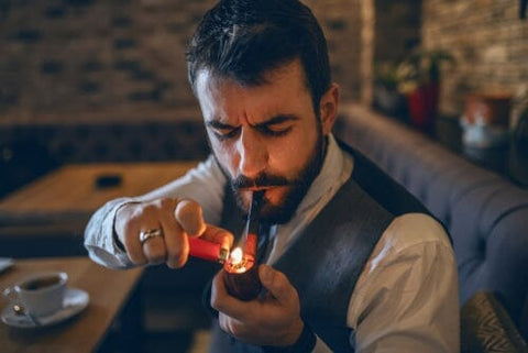 person lighting a tobacco pipe