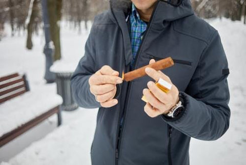 person holding a cigar outside in cold weather