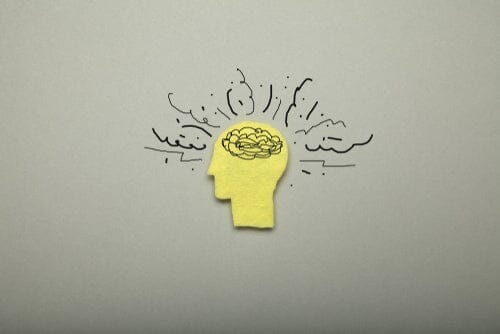a yellow cutout of a head with a scribbled brain, and squiggles coming out of the head